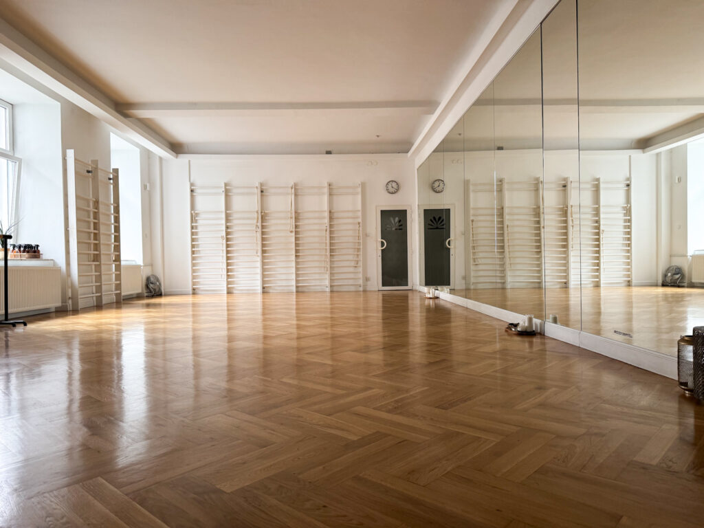 Duża sala do ćwiczeń w siedzibie Dobrzemitu z parkietem, lustrami na ścianie i drabinkami gimnastycznymi