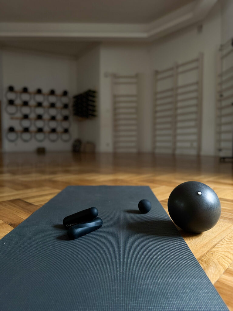 Mata do ćwiczeń z małą piłką i akcesoriami Pilates w sali Dobrzemitu; w tle parkiet i sprzęt przy ścianie